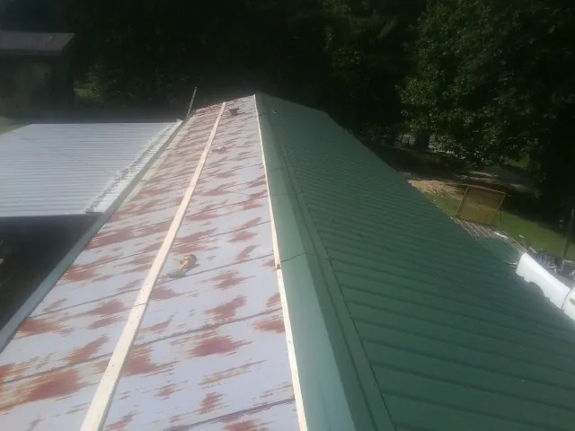 Old rusted panels beside newly installed green metal roofing — Wind Damage Roof Repair by Roofing Brothers in Lindstrom