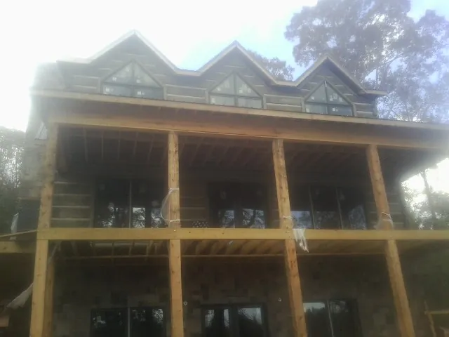 Dormers and porch framing on a large log home under construction — Roof Coating work by our crew in Lindstrom