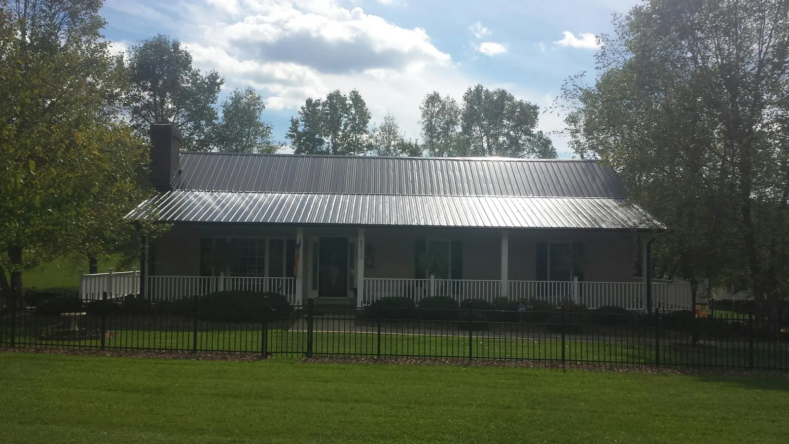 Gray metal roof on a brick ranch with a full width front porch — Gutter Guard Installation work by our crew in Lindstrom