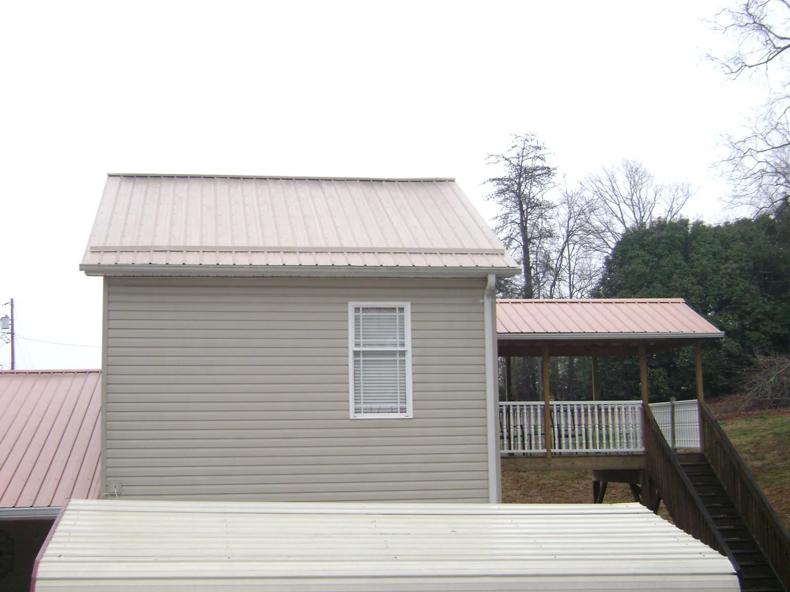 Tan metal roofs on a two story addition and attached porch, from a Roof Replacement job in Lindstrom